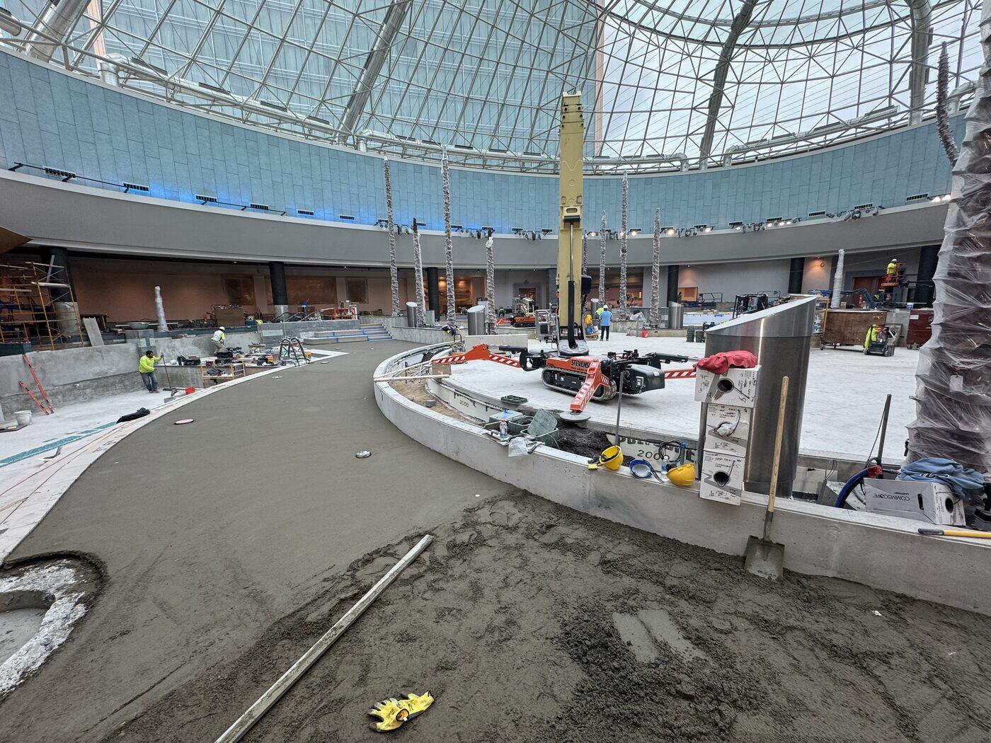 A mortar bed being floated across a curved commercial walkway beneath a glass dome.